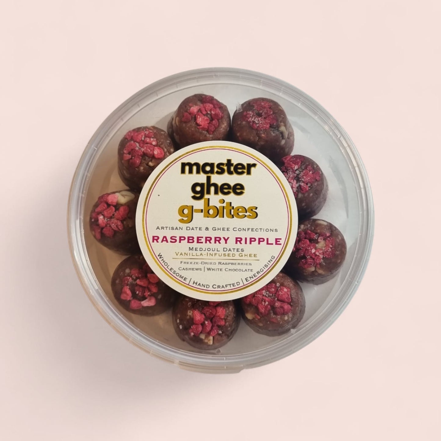 Container of Master Ghee G-Bites Raspberry Ripple on a light pink background